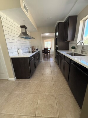 A kitchen with dark cabinets, a white countertop, and a tiled floor. - Come for the Views, Stay for the Escape (Green Valley)