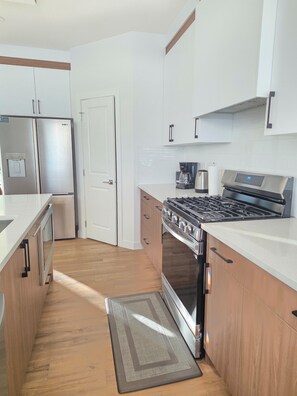 A modern kitchen with stainless steel appliances, wooden cabinets, and a built-in oven. - Fort Casamingo 3 bedroom, 3 full bath beautiful home/ Free Wifi (Fort Saskatchewan)