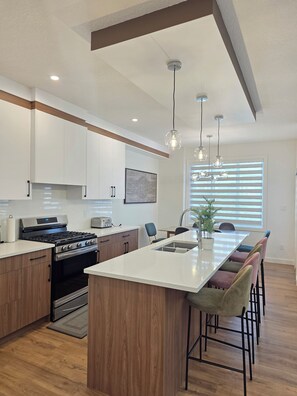 A modern kitchen with a central island, stainless steel appliances, and pendant lighting. - Fort Casamingo 3 bedroom, 3 full bath beautiful home/ Free Wifi (Fort Saskatchewan)