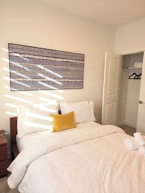 A hotel room with a bed, a bedside table, a nightstand, a wardrobe, and a large abstract painting on the wall. - Fort Casamingo 3 bedroom, 3 full bath beautiful home/ Free Wifi (Fort Saskatchewan)
