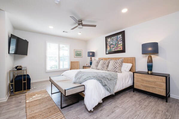 A bedroom with a bed, bedside tables, a ceiling fan, a TV mounted on the wall, and a window with blinds. - Charming 3-bedroom 2 bath house on Lake Hamilton in Hot Springs (Hot Springs)