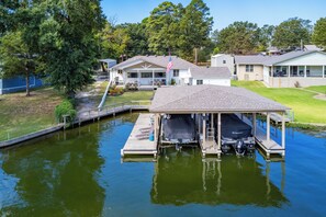 A waterfront property with a dock, a covered boat launch area, and a house with a porch. - Charming 3-bedroom 2 bath house on Lake Hamilton in Hot Springs (Hot Springs)