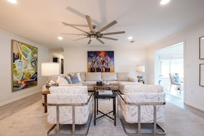 A modern living room with a ceiling fan, a large abstract painting, a sofa set, and a coffee table. - Charming 3-bedroom 2 bath house on Lake Hamilton in Hot Springs (Hot Springs)