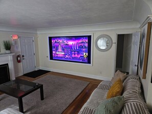 Una sala de estar con un televisor de pantalla plana montado en la pared, un sofá, una mesa de centro y una chimenea.