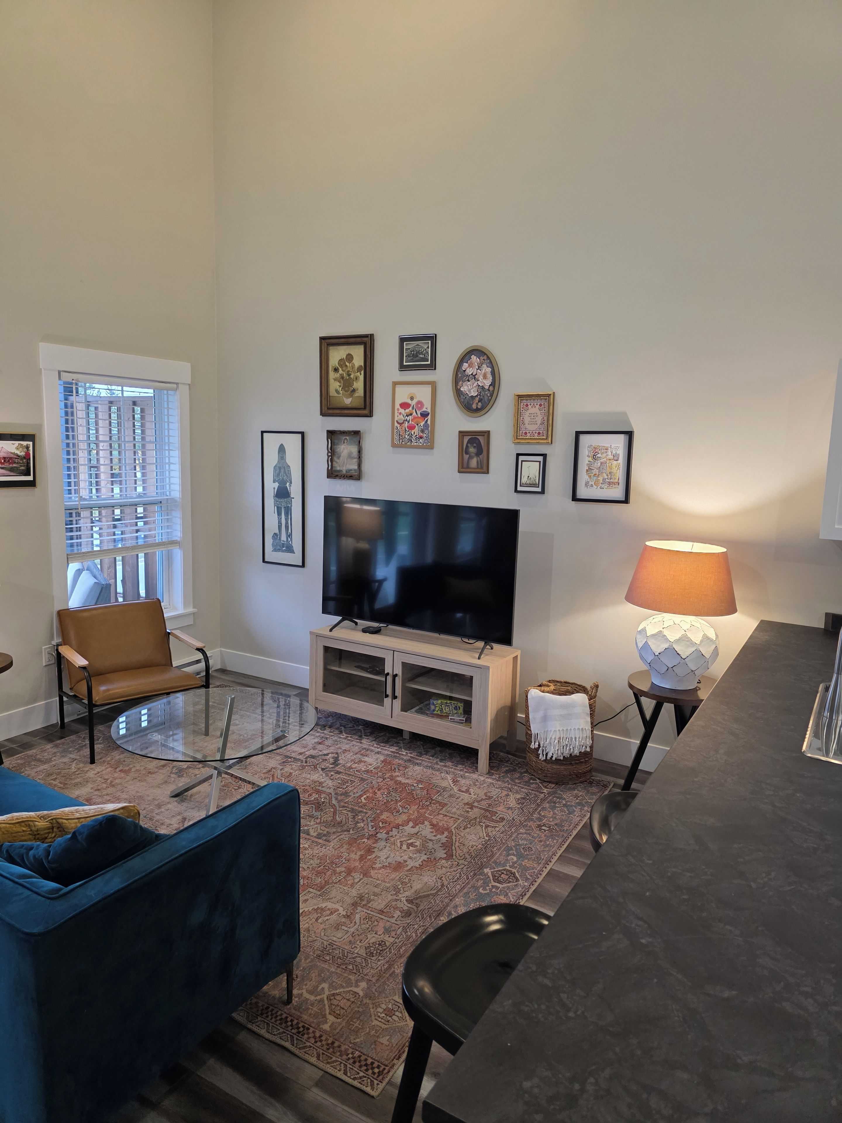 Un salon avec un téléviseur, un canapé, une table basse, un tapis et une lampe.