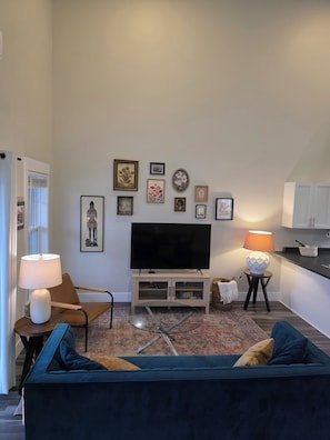 Una sala de estar con televisor, sofá y varias fotografías enmarcadas en la pared.