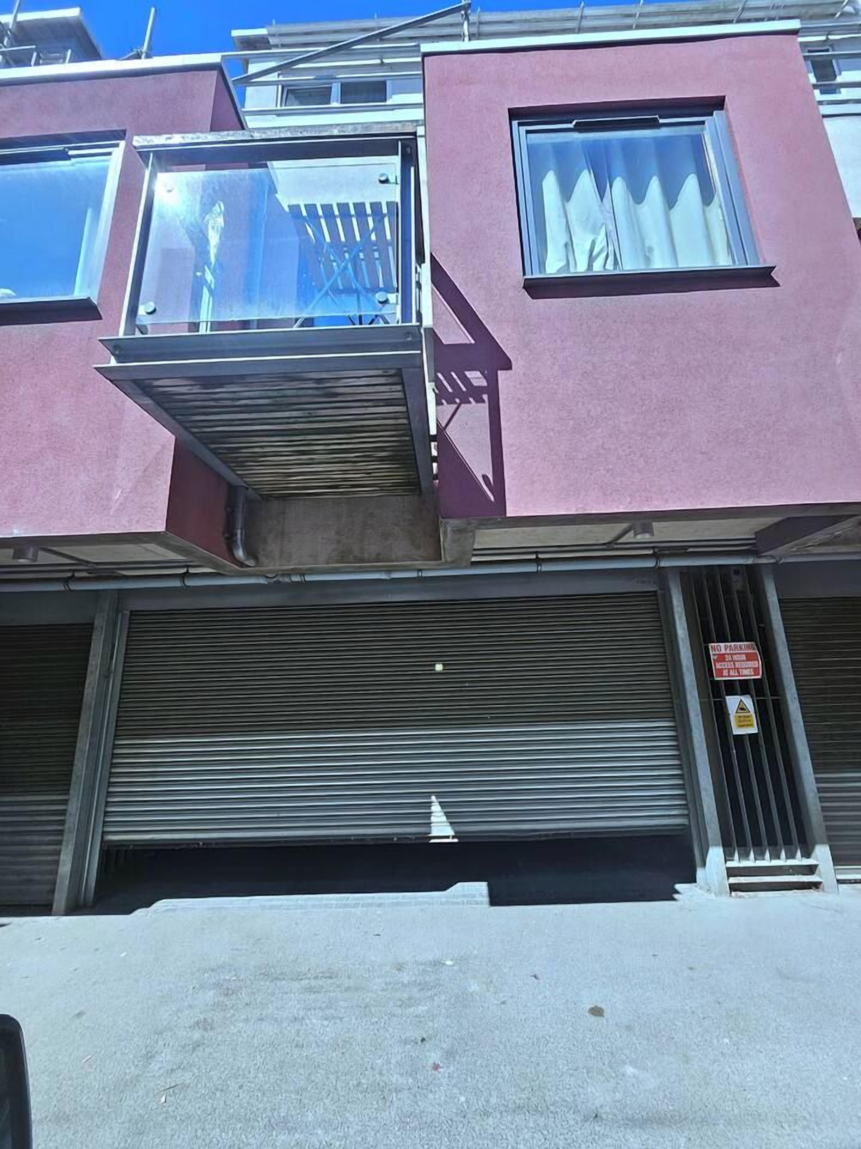 A building with a closed shuttered storefront and a visible 'NO PARKING' sign.