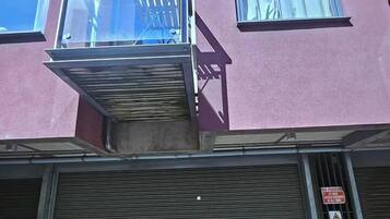 A building with a closed shuttered storefront and a visible 'NO PARKING' sign.
