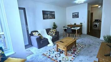 A modern living room with a sofa, coffee table, and a dining area with chairs and a table.