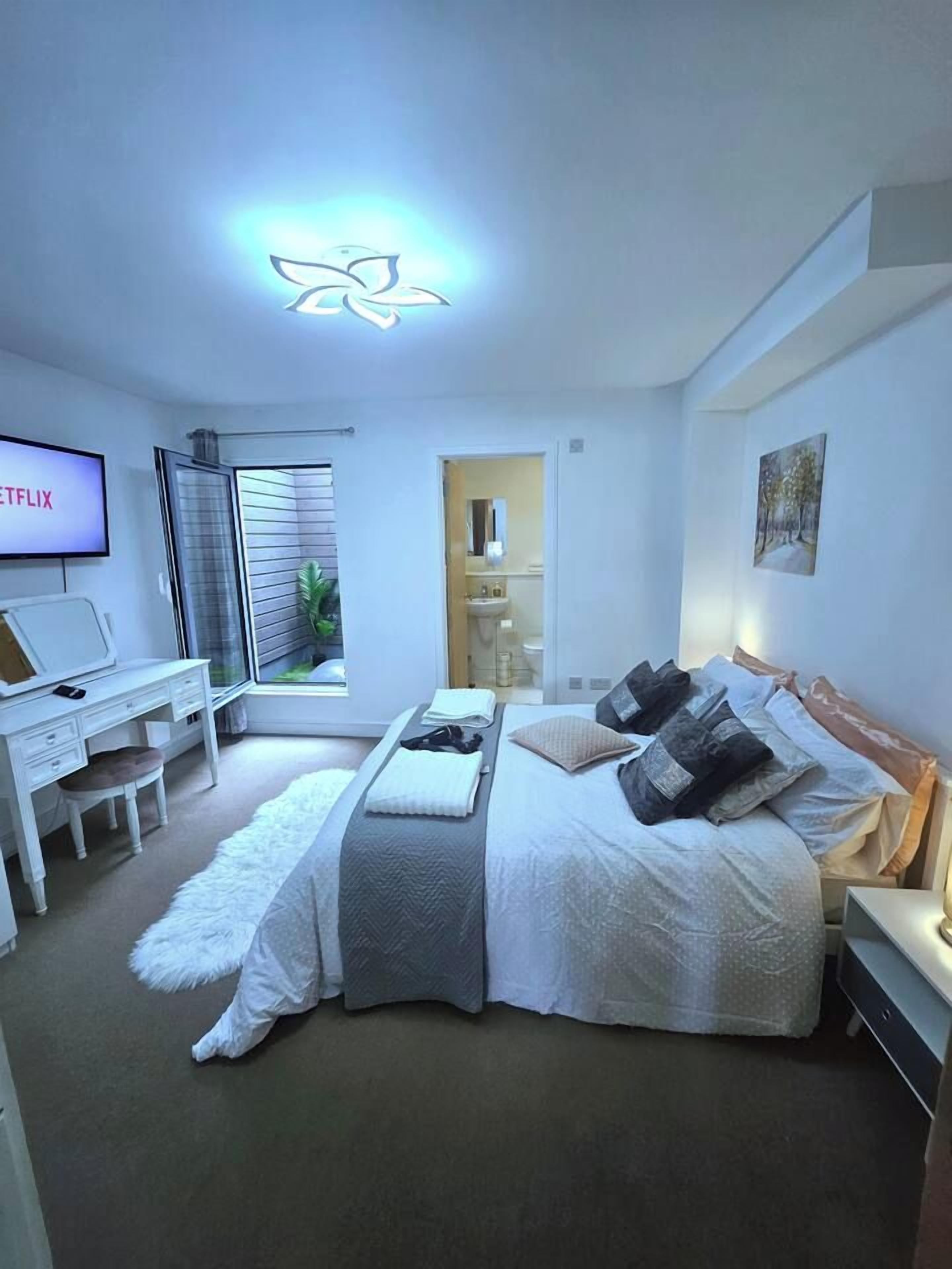 Une chambre à coucher avec un lit, un bureau, une télévision et une fenêtre.