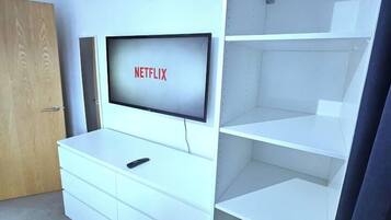 A room with a white entertainment unit, a television displaying 'NETFLIX,' and a door.