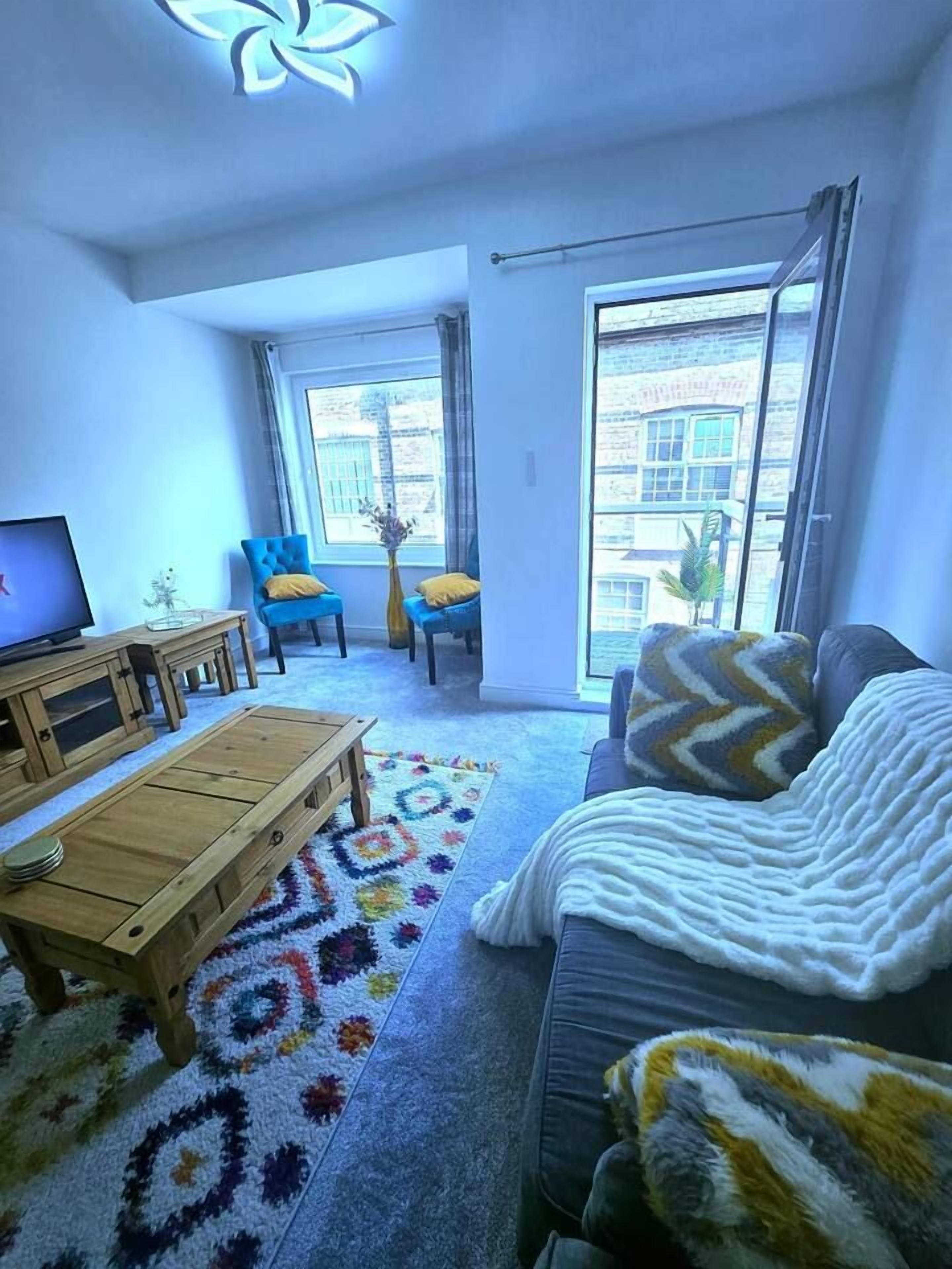 A living room with a sofa, a coffee table, a TV, and a large window.