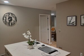 A room with a white marble table, a clock, a potted orchid, a laptop, and a water bottle. - Private 3BR Retreat with Free Parking near Hartford Attractions (Hartford)