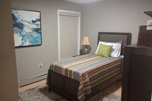 A bedroom with a bed, a nightstand, a lamp, a painting on the wall, and a door. - Private 3BR Retreat with Free Parking near Hartford Attractions (Hartford)