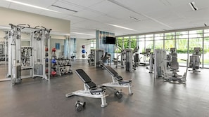 Ein Fitnessstudio mit verschiedenen Trainingsgeräten, darunter Kraftgeräte, Kurzhanteln und Cardiogeräte.