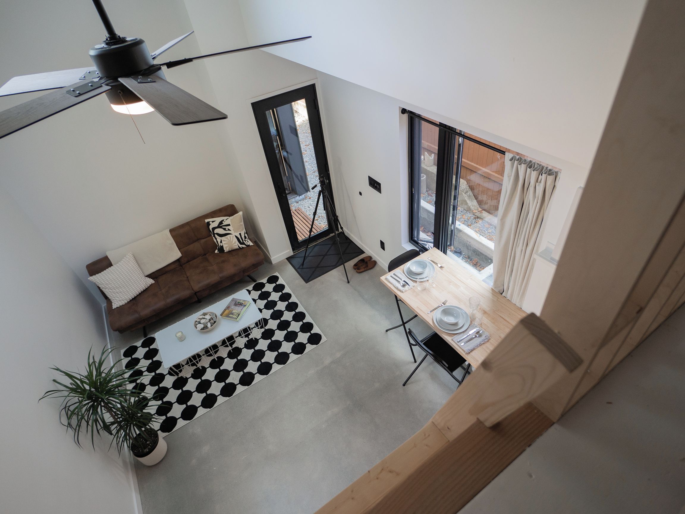 A modern living space with a sofa, dining table, and a ceiling fan.