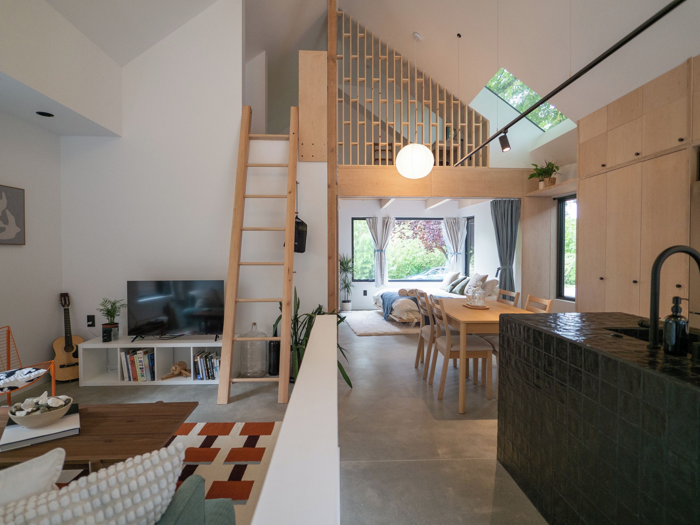 A modern interior with a loft bedroom, a dining area, and a kitchen.