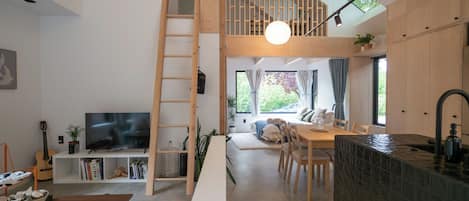 A modern interior with a loft bedroom, a dining area, and a kitchen.