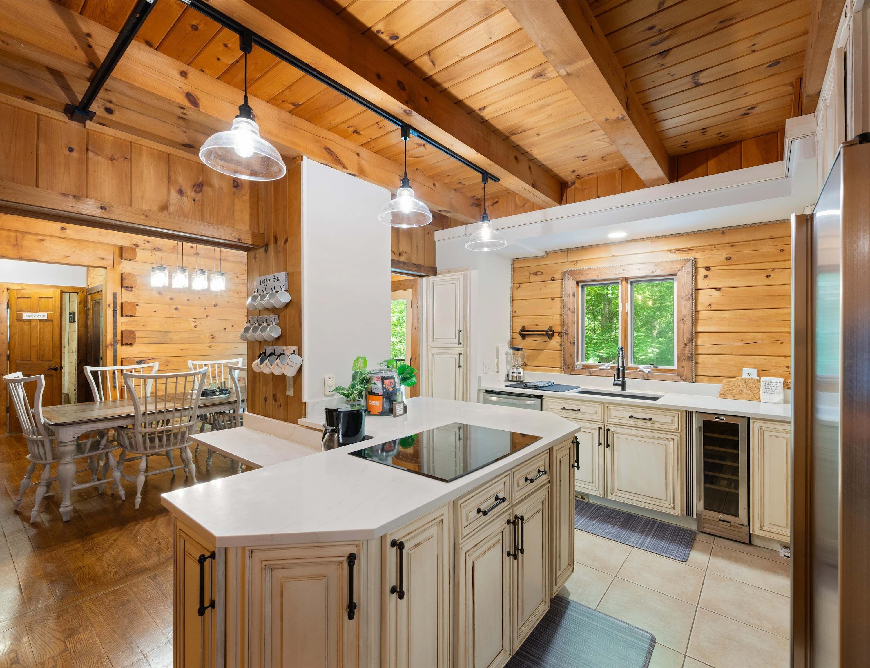 A kitchen with wooden walls, a central island, and pendant lighting.