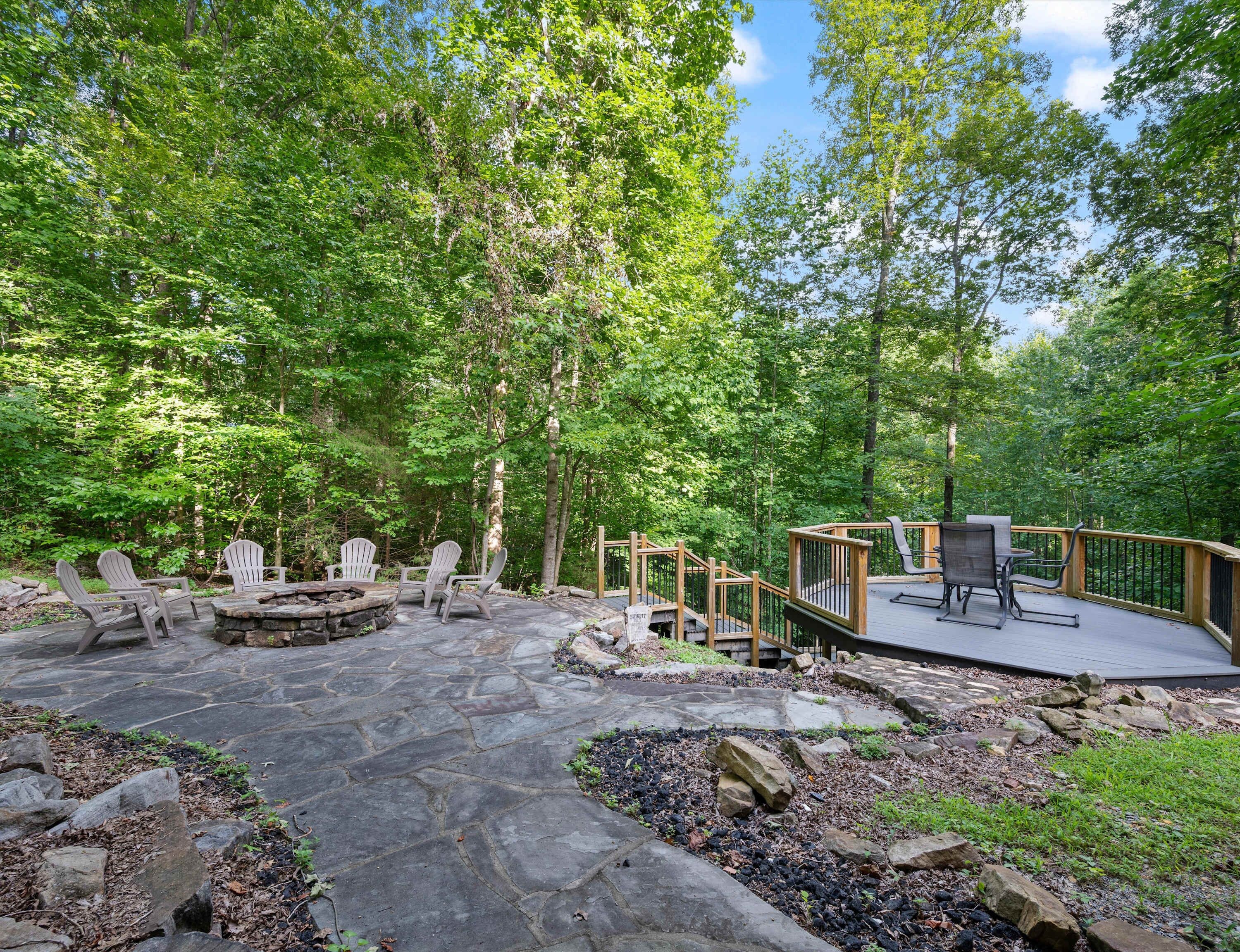 An outdoor deck with Adirondack chairs, a fire pit, and a wooden deck railing.