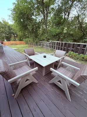 Eine Terrasse im Freien mit Tisch und Stühlen, umgeben von einem Holzzaun und Bäumen.