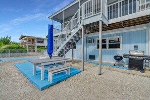 A covered outdoor area with a barbecue grill, a picnic table, and a staircase leading to a balcony. - Sombrero Beach Hideaway | Dockage, Close to Beach (Marathon)