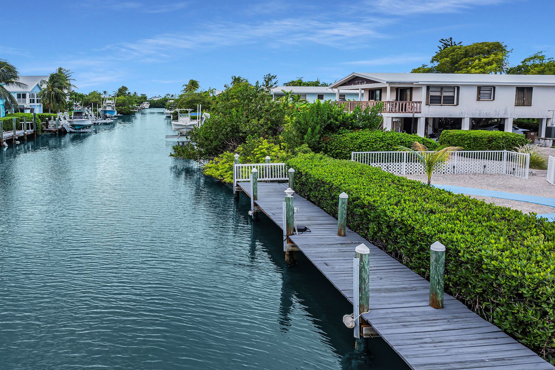 A waterfront property with a dock, boats, and lush greenery.