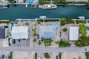 Vista aérea de uma marina com barcos atracados, piscina e edifícios com telhados planos.
