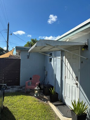 A residential property with a garage, a red chair, a potted plant, and a clear blue sky. - Charming studio in Hollywood with fabulous kitchen (Hollywood)