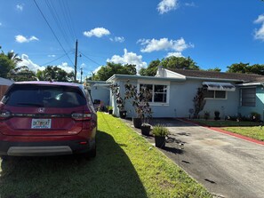 A red car parked in front of a house with a white exterior and a garage. - Charming studio in Hollywood with fabulous kitchen (Hollywood)
