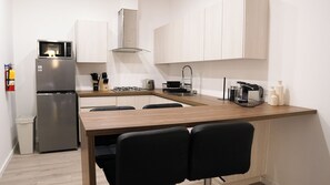 Eine kompakte Küche mit Kühlschrank, Mikrowelle, Gasherd und einer Kaffeemaschine.