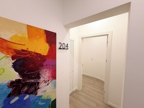 Ein Flur mit einem farbenfrohen, abstrakten Gemälde links und einer Tür mit der Nummer 204 rechts.