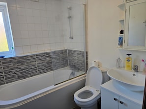 Et badeværelse med badekar, toilet og håndvask.