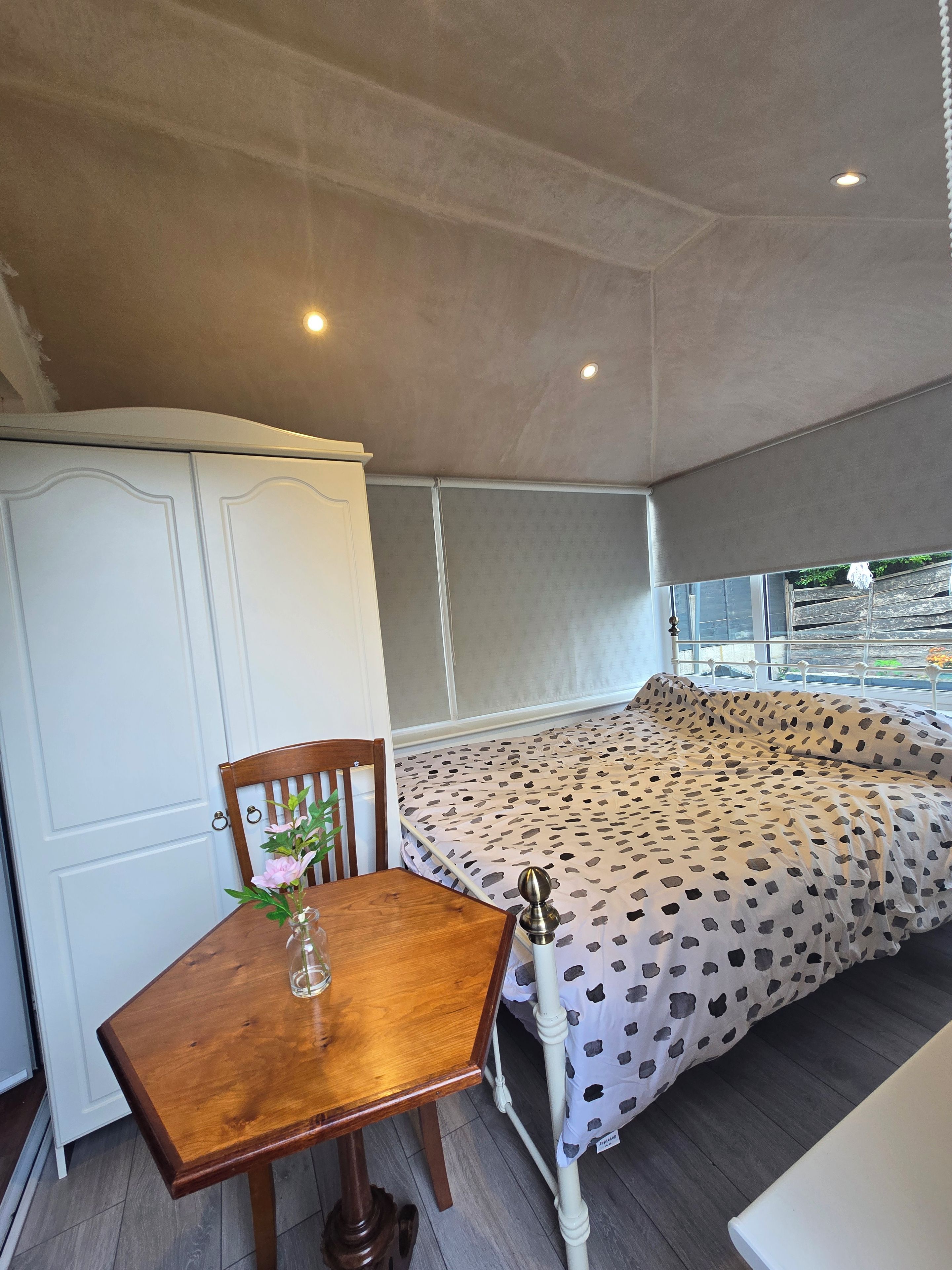 A room with a bed, a table with a chair, and a wardrobe.