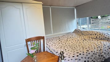 A room with a bed, a table with a chair, and a wardrobe.