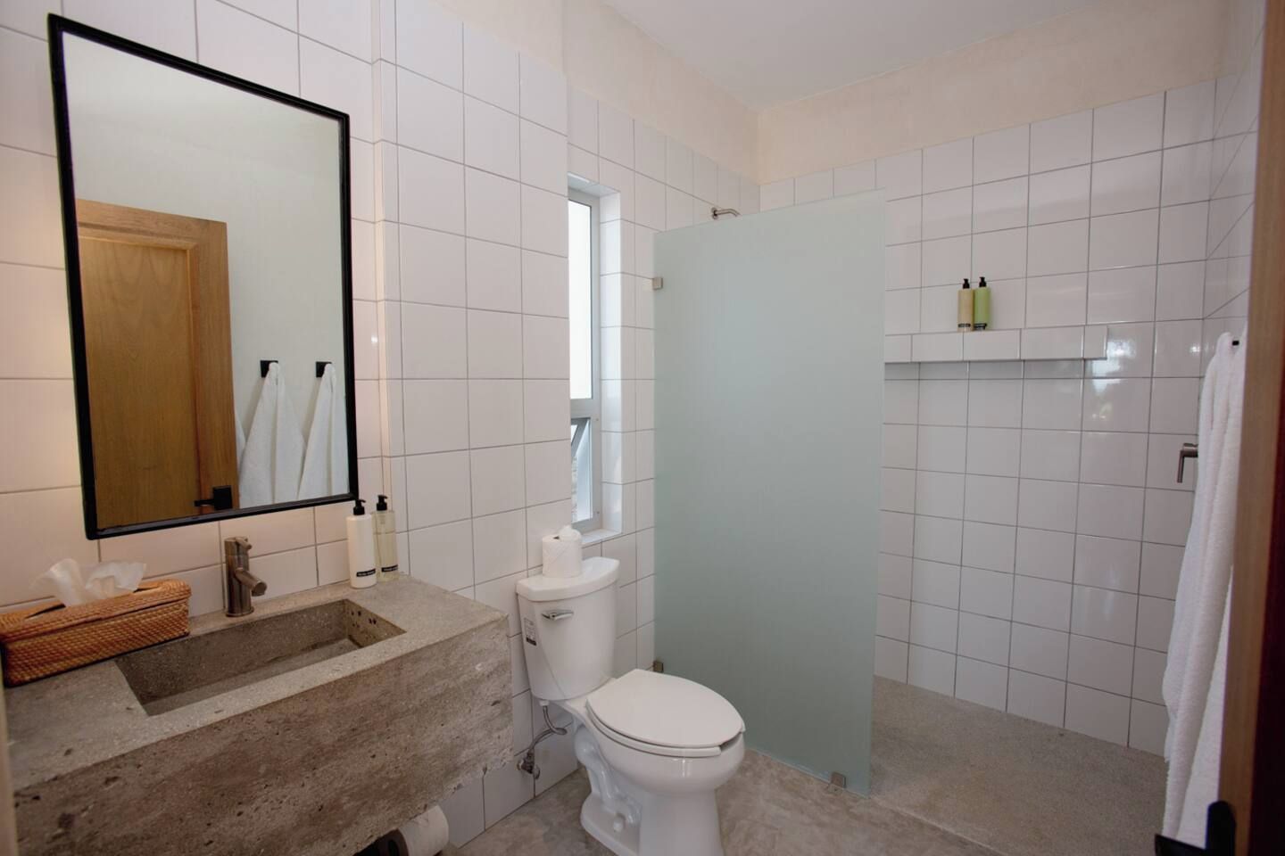 Un baño con lavamanos, inodoro, espejo y zona de ducha.