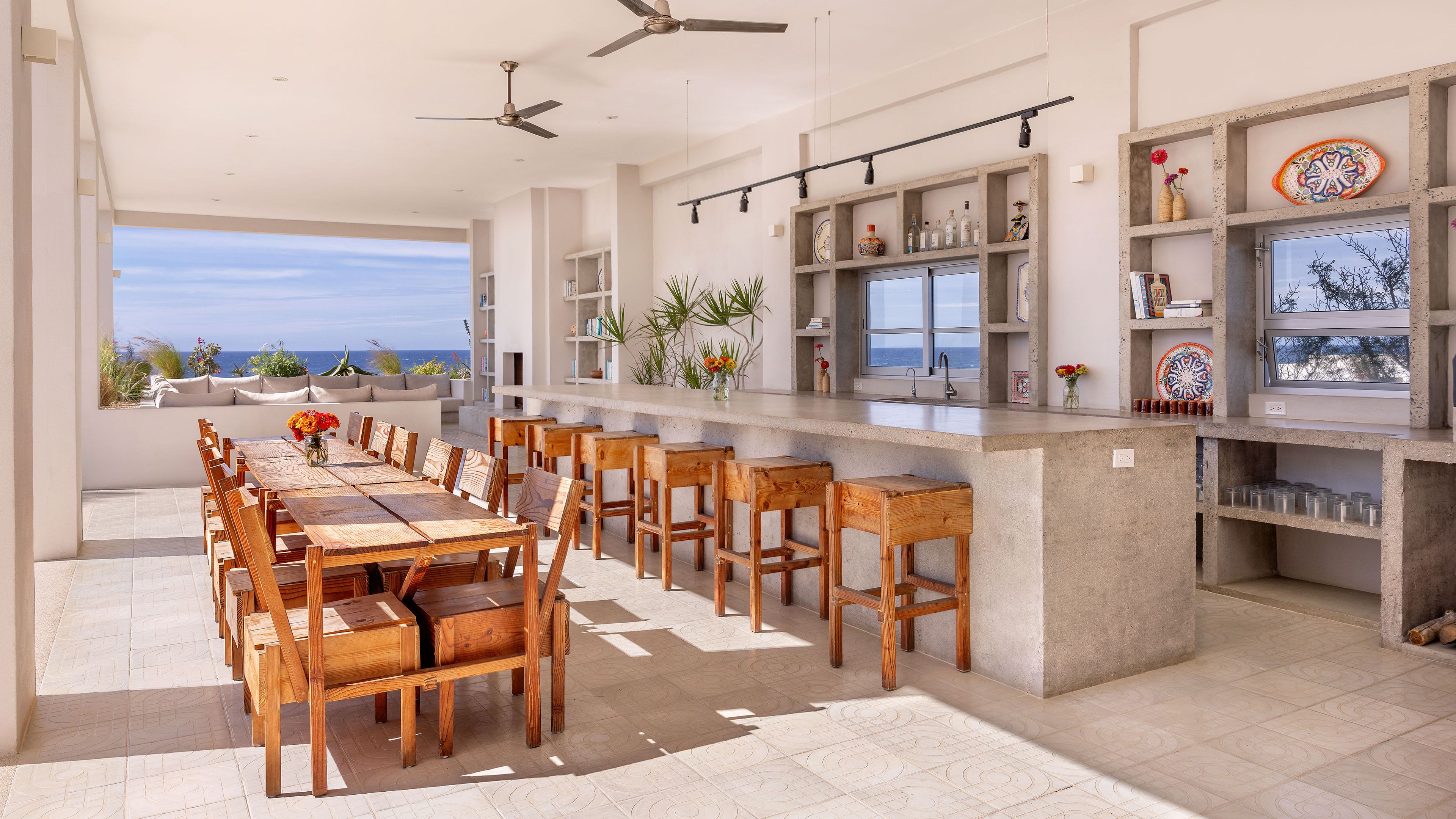 Una cocina moderna con barra, muebles de madera y vista al mar.