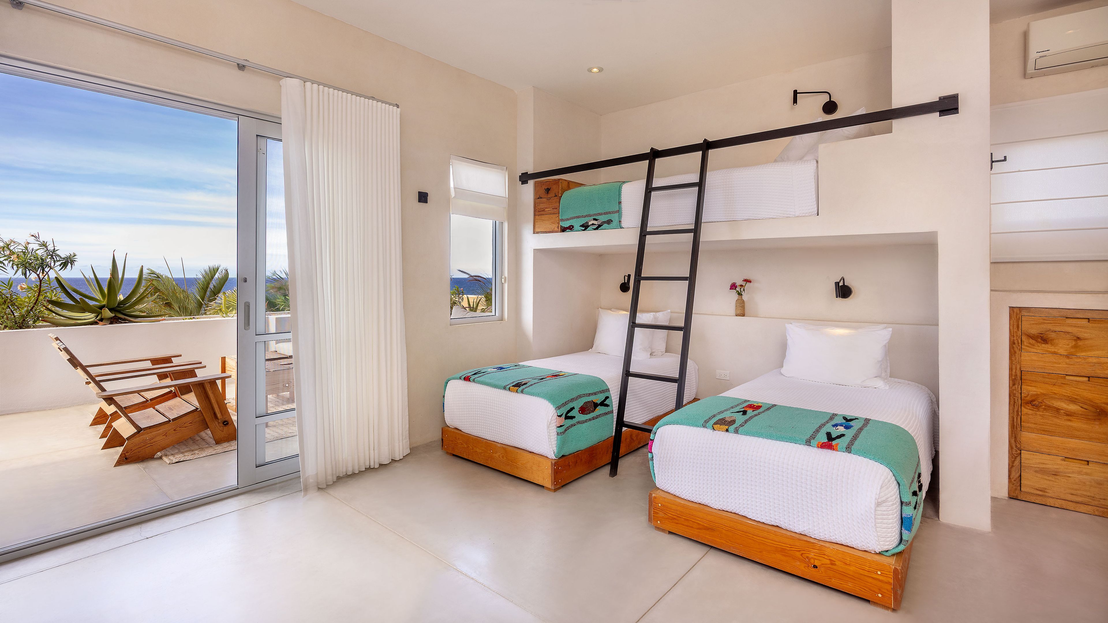 Una habitación con dos camas, un balcón con mesa y sillas, y vista al océano.