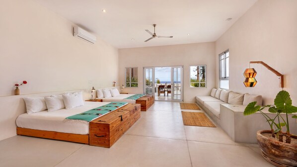 Habitación de hotel moderna con una cama grande, un sofá, zona de comedor y vistas al exterior.