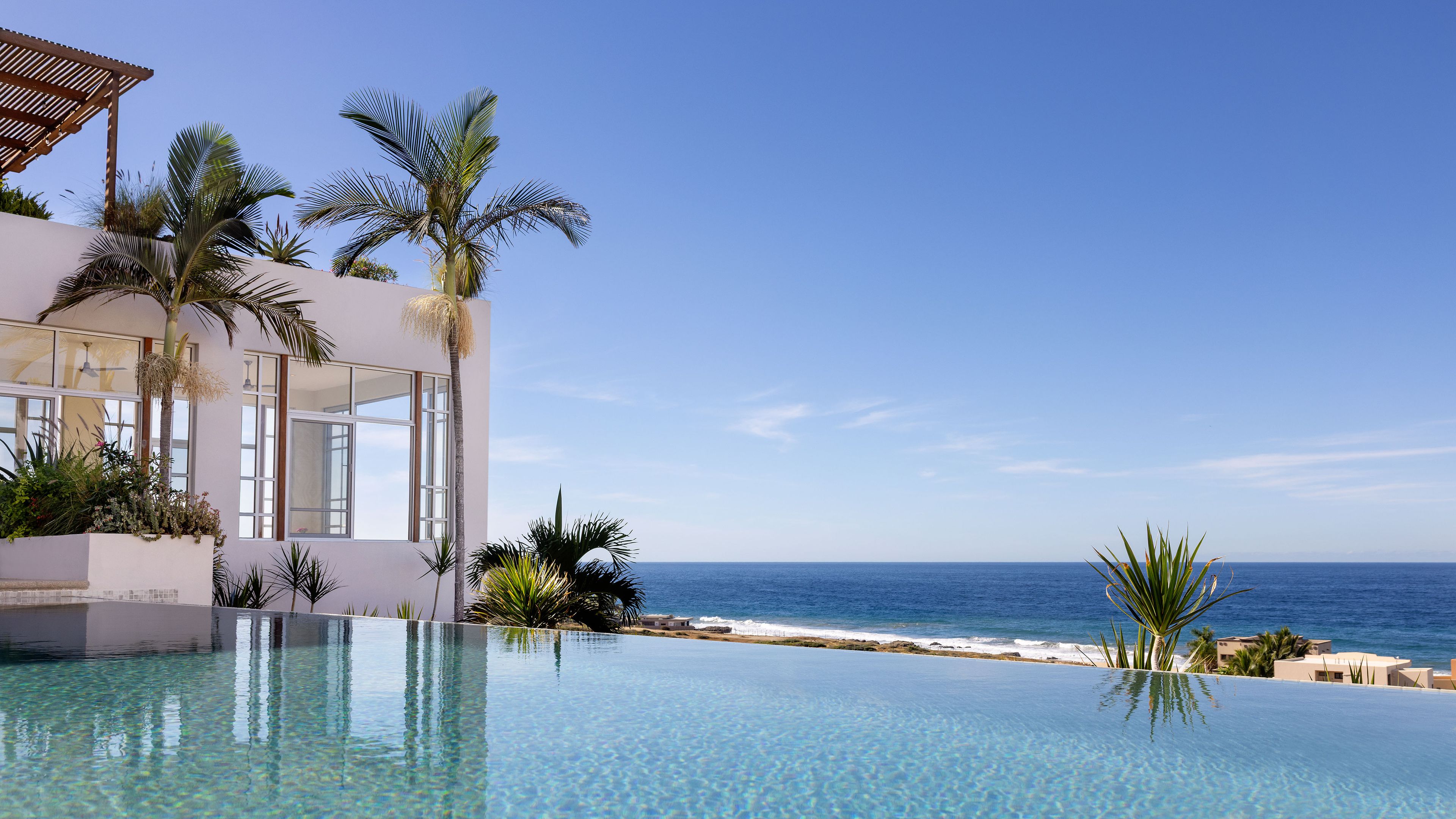 Un resort moderno con piscina infinita con vistas al océano.