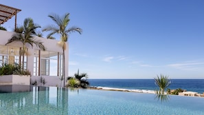 Un resort moderno con piscina infinita con vistas al océano.