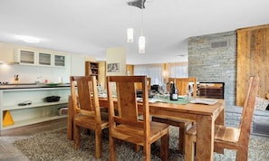 A dining area with a wooden table and chairs, a stone wall, and a kitchen in the background. - SPACIOUS MOUNTAIN APARTMENT WITH LARGE SOUTH-FACING BALCONY (Zermatt)