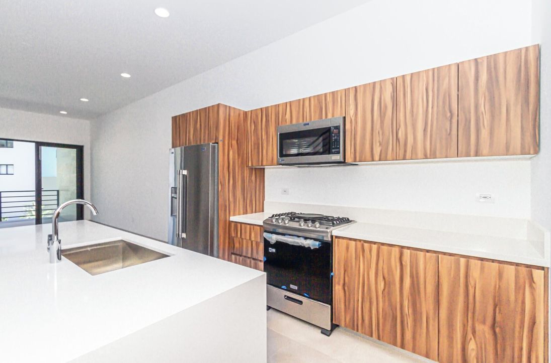 A modern kitchen with a stainless steel refrigerator, a microwave, and a gas stove.