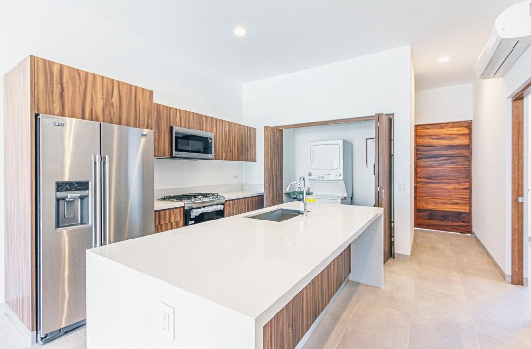 A modern kitchen with stainless steel appliances, a central island, and wooden cabinetry.
