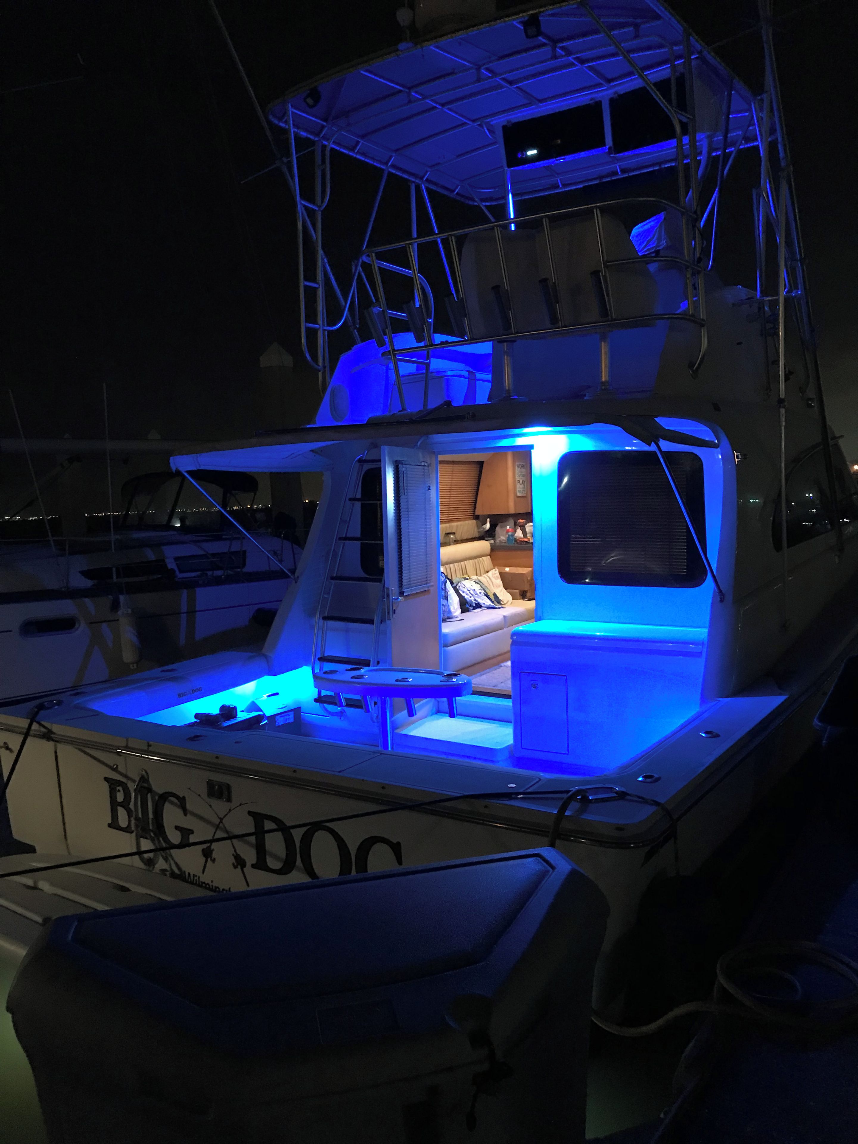 Un bateau doté d’un espace intérieur éclairé d’une lumière bleue, d’une cuisine visible et d’une échelle menant au pont supérieur.