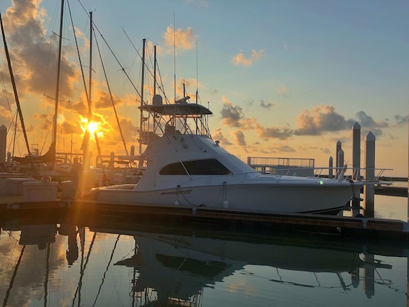 Un yate amarrado en un puerto deportivo con el atardecer al fondo.