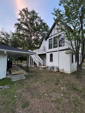 Ein zweistöckiges Haus mit einer Garage und einem überdachten Balkon, verbunden durch eine Treppe sowie einem Rasen.