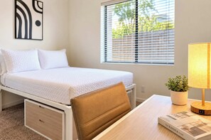 A bedroom with a bed, a desk with a lamp, a chair, and a window with blinds. - Boulevard Stays Modern Tempe 4BR ASU Pool, Gym (Tempe)