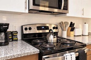A modern kitchen with a stainless steel stove, a kettle, and a microwave above it. - Boulevard Stays Modern Tempe 3BR ASU Pool, Gym (Tempe)