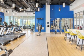 Ein Fitnessstudio mit Laufbändern, Trainingsgeräten und gelben Stühlen.